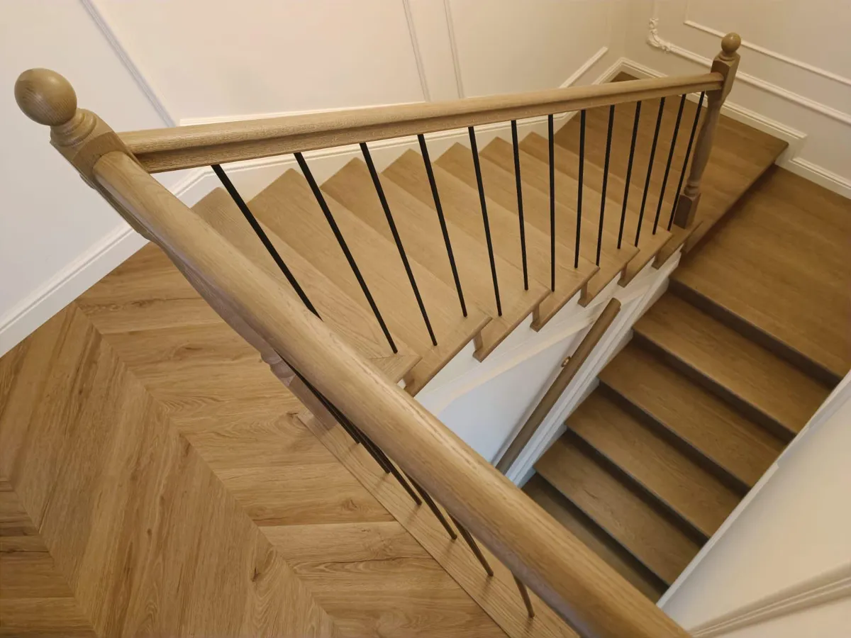 Solid oak handrail with turned newel posts and black steel balusters