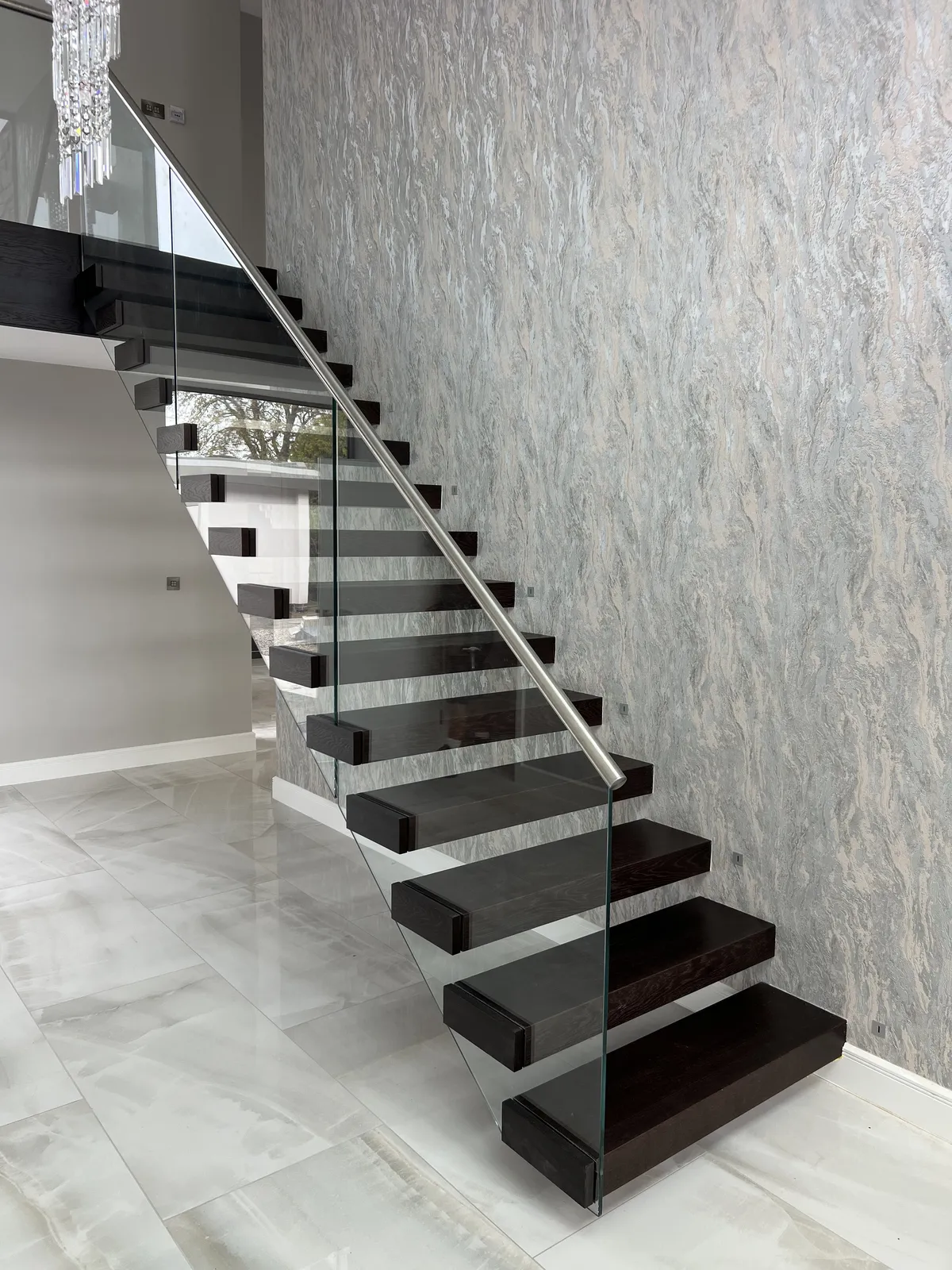 Floating cantilever staircase with dark-stained oak treads and a frameless glass balustrade